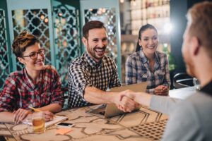 Man shaking hands over a table with other colleagues