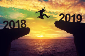 Silhouetted figure jumping from a ledge labelled 2018 to another ledge labelled 2019