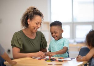 A teacher and child work creatively at a table in a classroom setting
