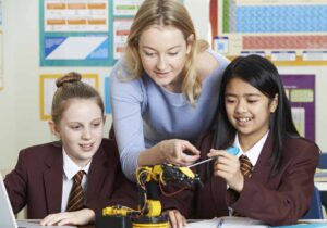A school teacher is helping two pupils in a classroom setting