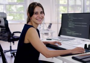 Female embedded computing expert is working in the office with multiple coding screens