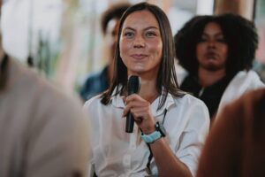A public health practitioner sits in an audience with a microphone