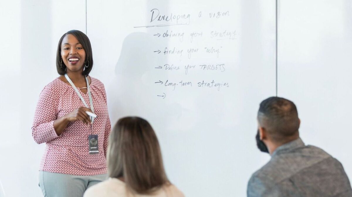 Female workplace trainer in front of whiteboard - Learning at Work blog