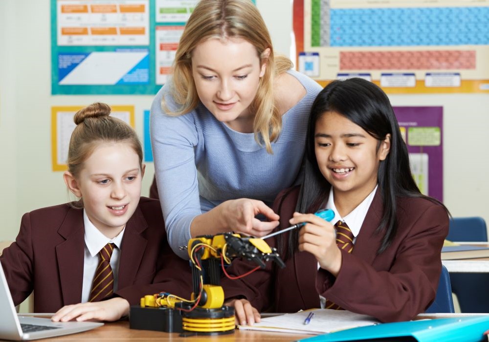 A school teacher is helping two pupils in a classroom setting