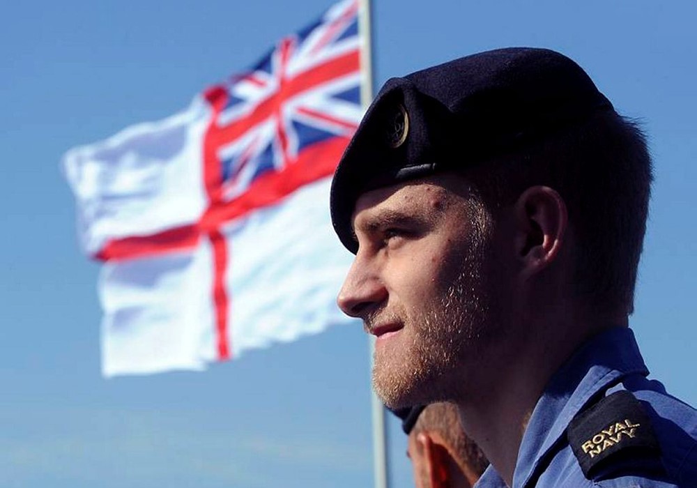 Royal Navy Personnel standing in front of a British flag