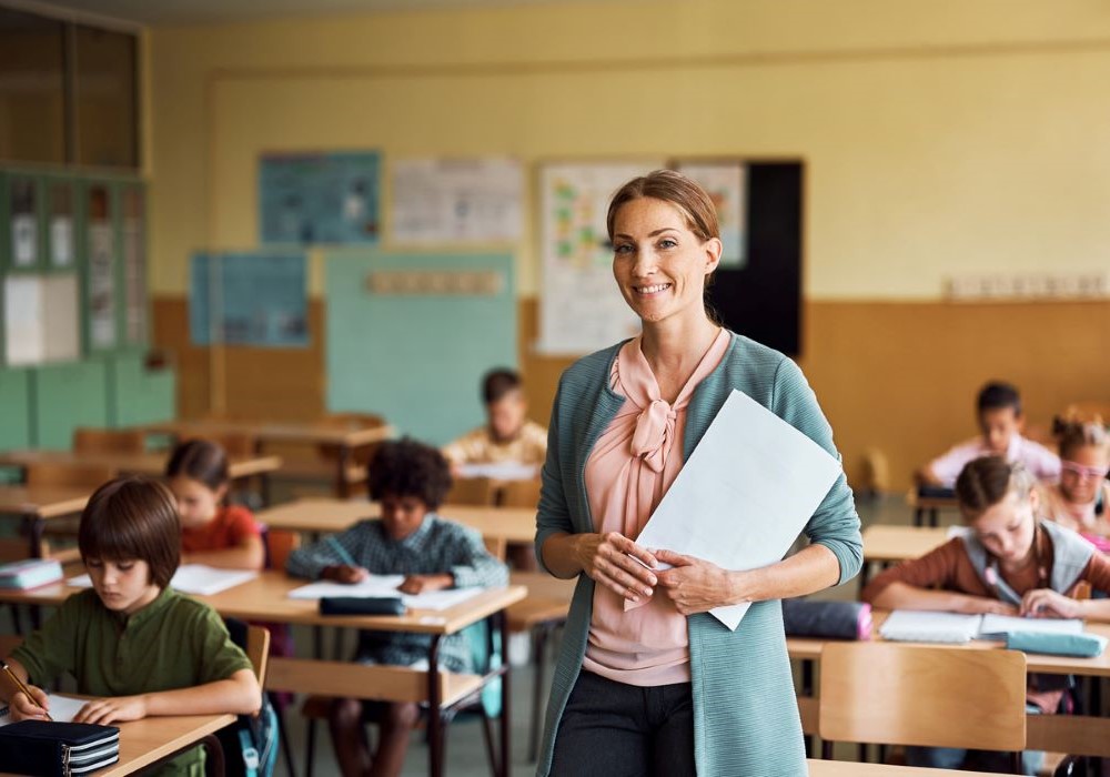 Education with Early Childhood MA - a teacher stands in a classroom fall of young children