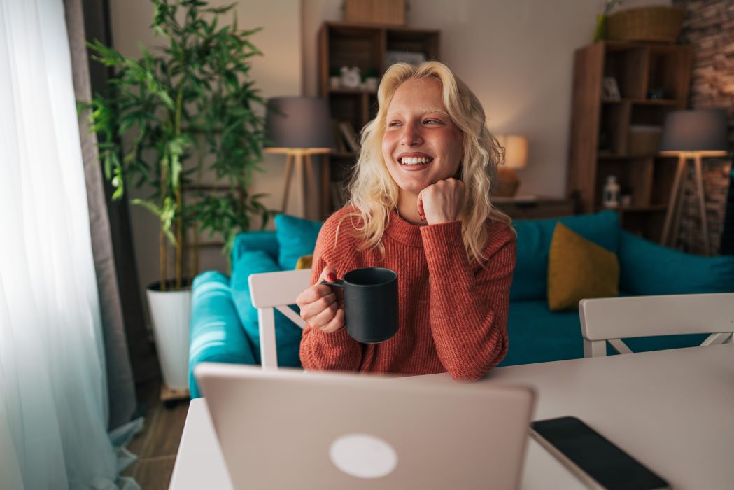 Young woman working remotely from home reflecting on her work