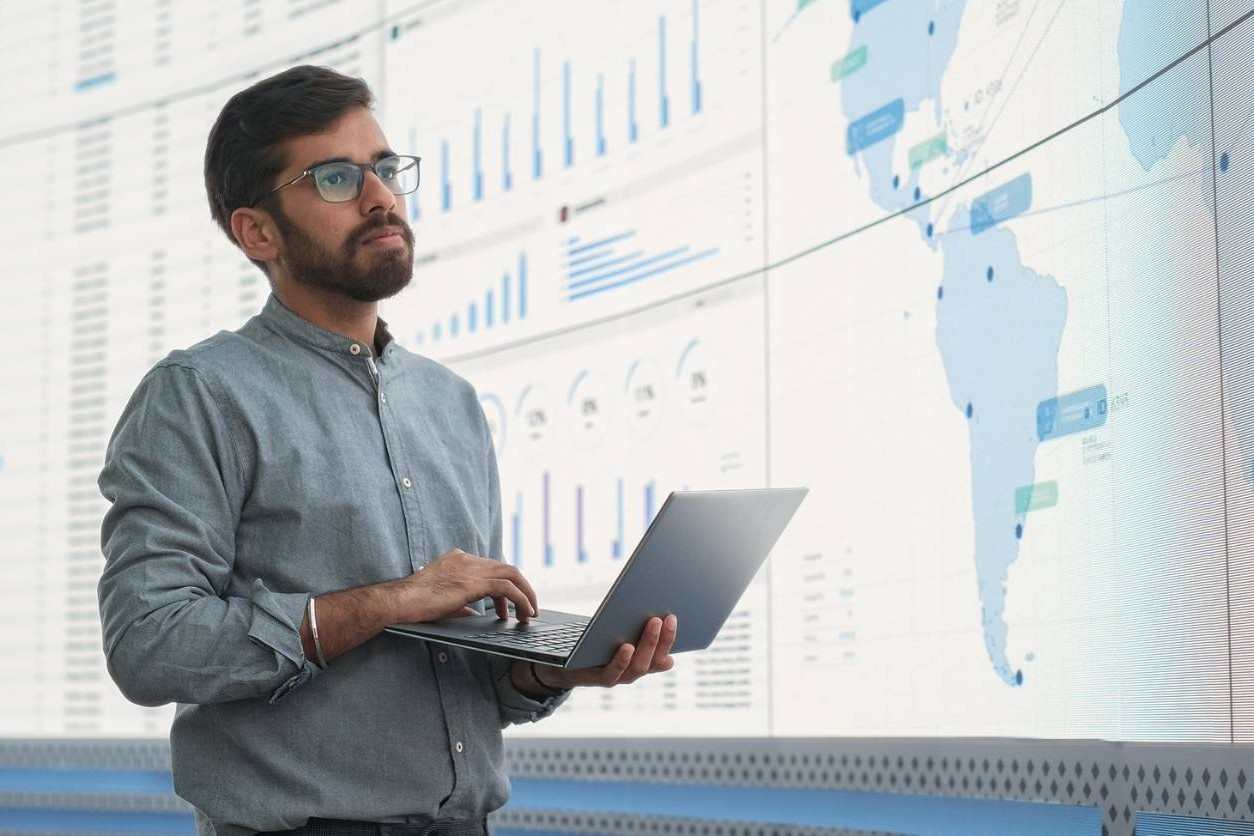 International business manager looking at business analytics while holding his laptop