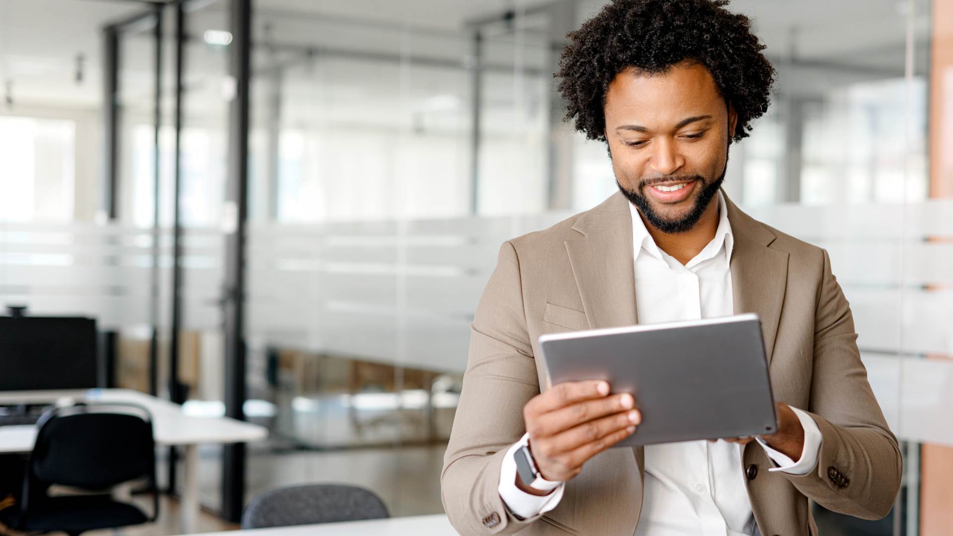 A young confident business man preparing a public value report on his digital tablet.